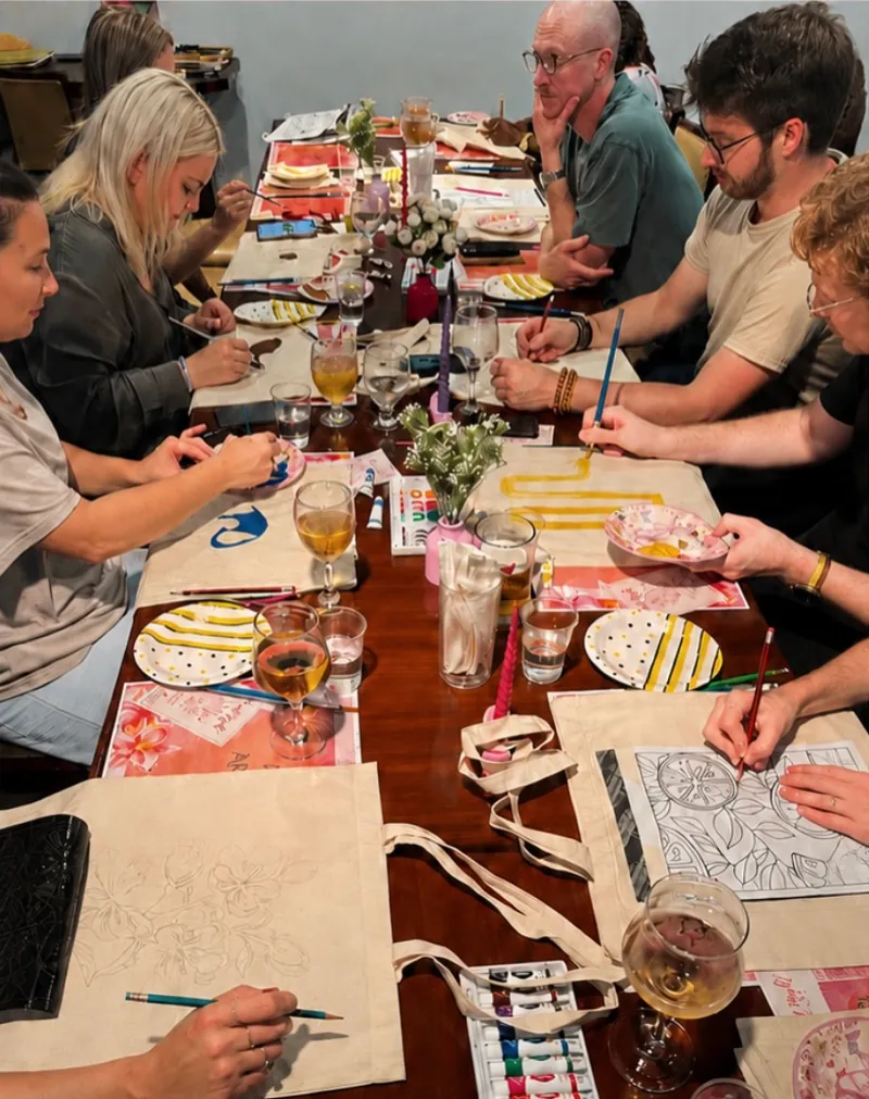 Guests painting tote bags together around an Art Nook workshop table