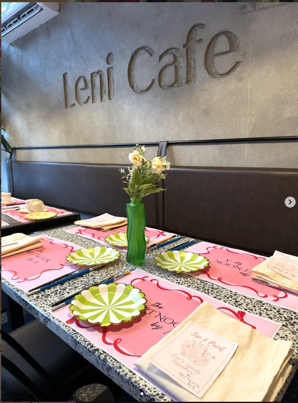 The Art Nook workshop setup at Leni Café, with pink place mats, brushes, totes and green scalloped plates